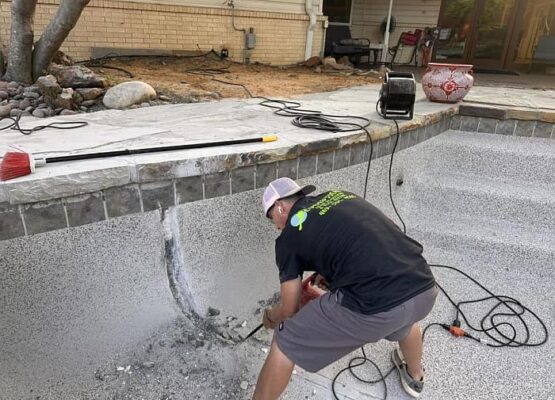 Crack Repair Additional Empty pool with fresh pebble finish, stone coping, and visible wall fittings.