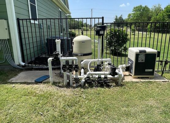 Pool Equipment Fix Completed Pool equipment setup with filter, pipes, and heater beside a fence.