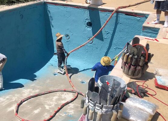 Pool Remodeling In Progress Workers resurfacing an empty swimming pool during renovation